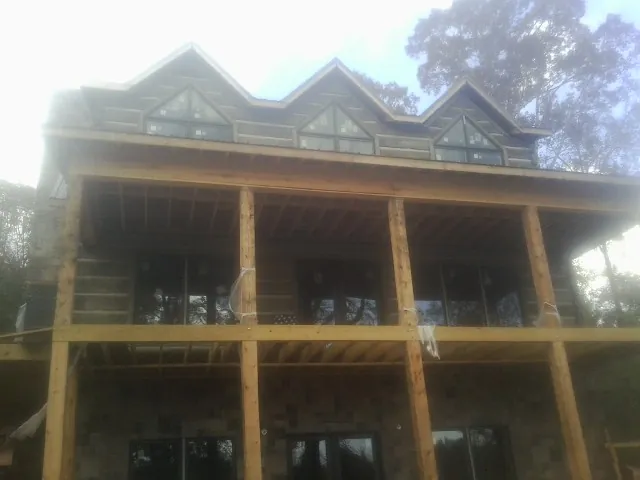 Dormers and porch framing on a large log home under construction — Roof Coating work by our crew in Red Oak